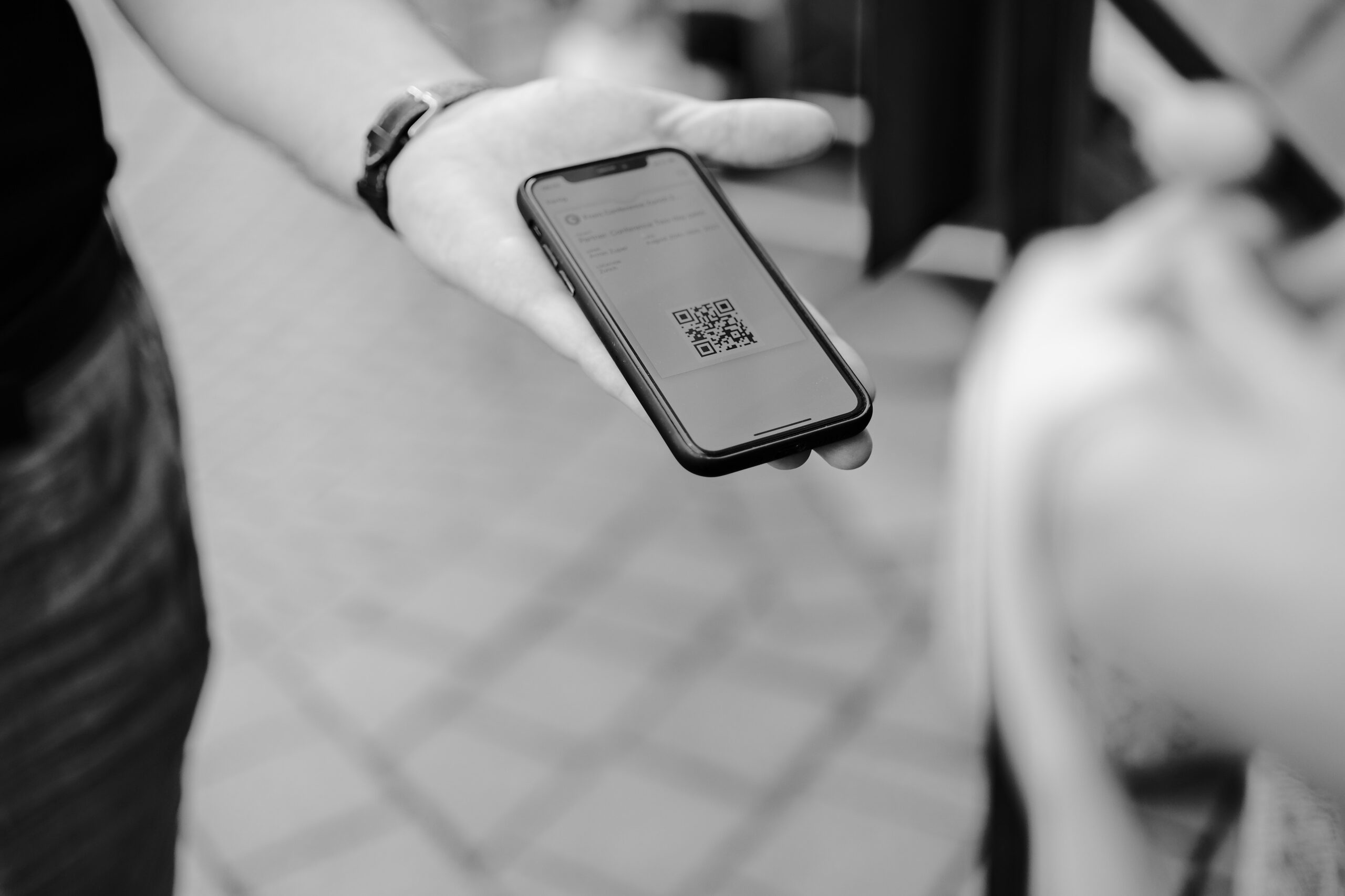 person holding a cell phone showing a QR code on the screen.