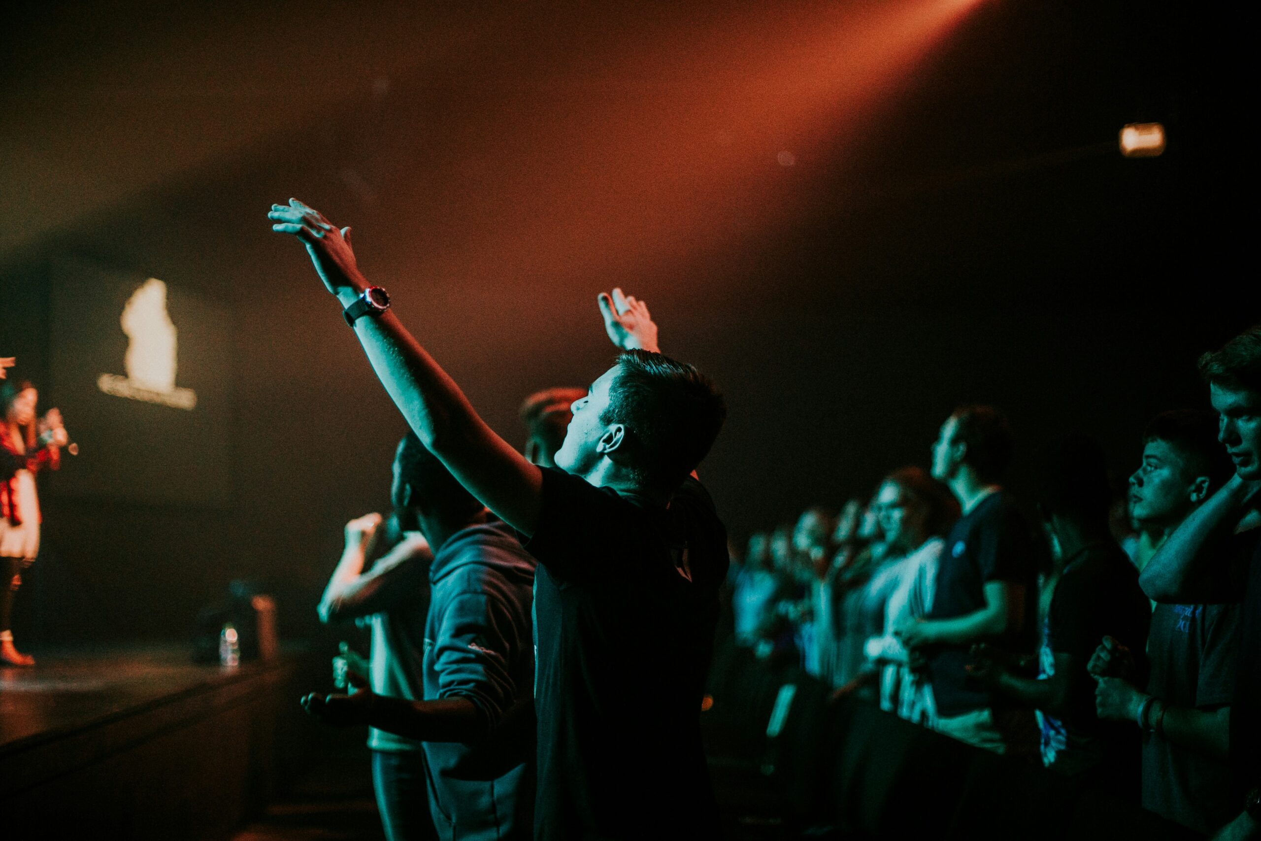 student raising hands in worship service at camp