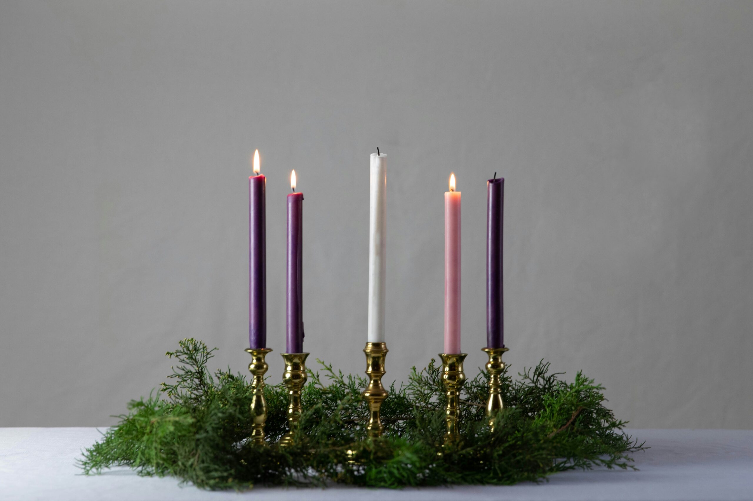 lit advent candles with christmas wreath surrounding them